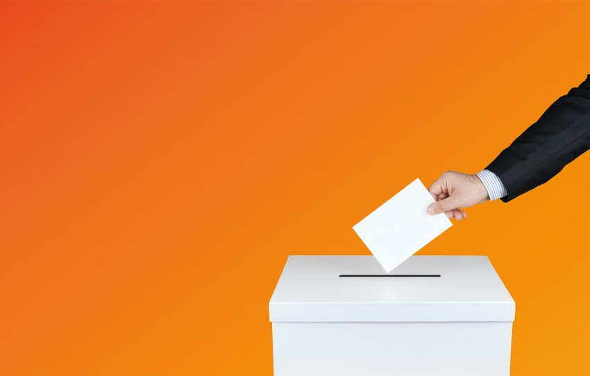 A hand putting a ballot into a box against an orange background