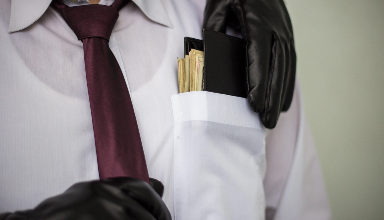 Gloved hand stealing money out of man's shirt pocket Gloved hand stealing money out of man's shirt pocket