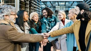 A group of individuals all shaking hands in a sign of teamwork A group of individuals all shaking hands in a sign of teamwork