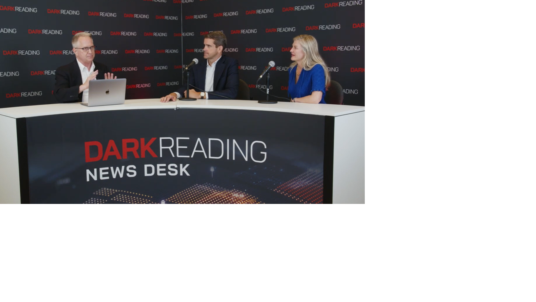 Two people talking at a news desk against a dark backdrop with "Dark Reading" written on it.