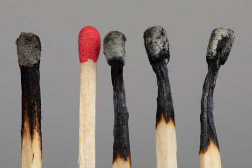 Photo of five wooden matches, four of which have been burned and extinguished, leaving one red-tipped one unburned