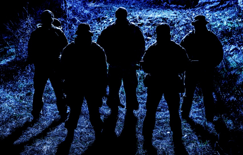 Shadowy group of armed soldiers patrolling area at night