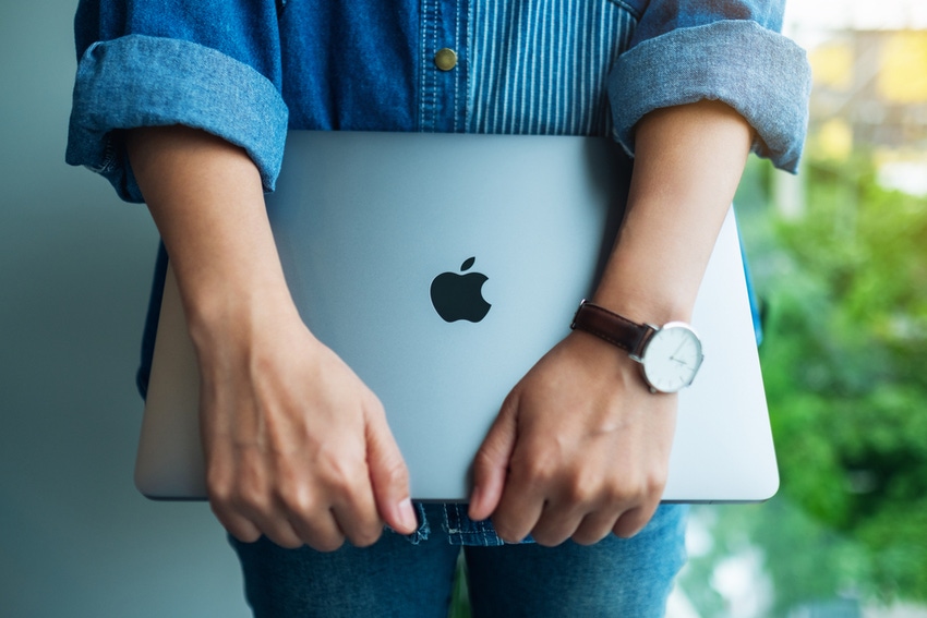 woman standing and holding an Apple MacBook Pro laptop computer