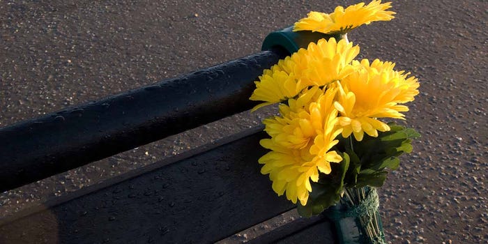 bouquet of yellow flowers tied to a park bench.