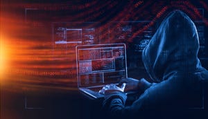 A hooded hacker on a laptop with red code flowing through from the left side of the image