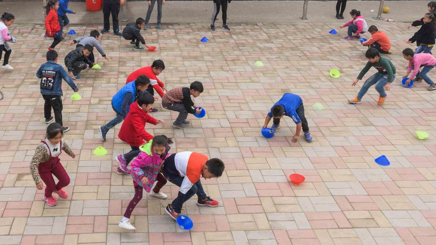 Students in a schoolyard play the game capture-the-flag.