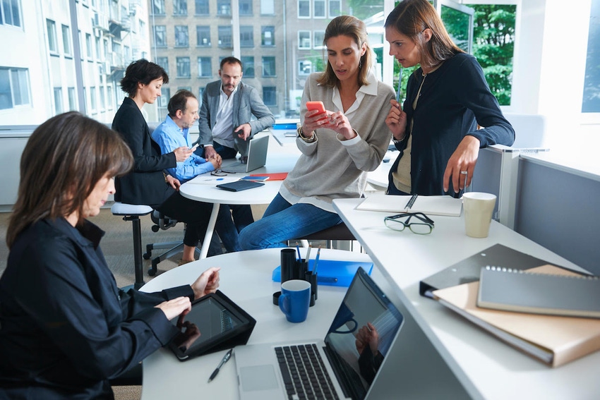 A group of business women discussing something with people in the background