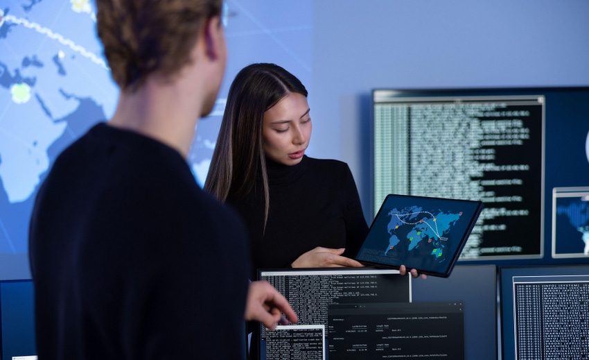 Two people, a man and a woman, work in a security operations center (SOC)
