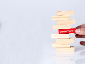Jenga blocks with one red block having the word "commitment" on it 