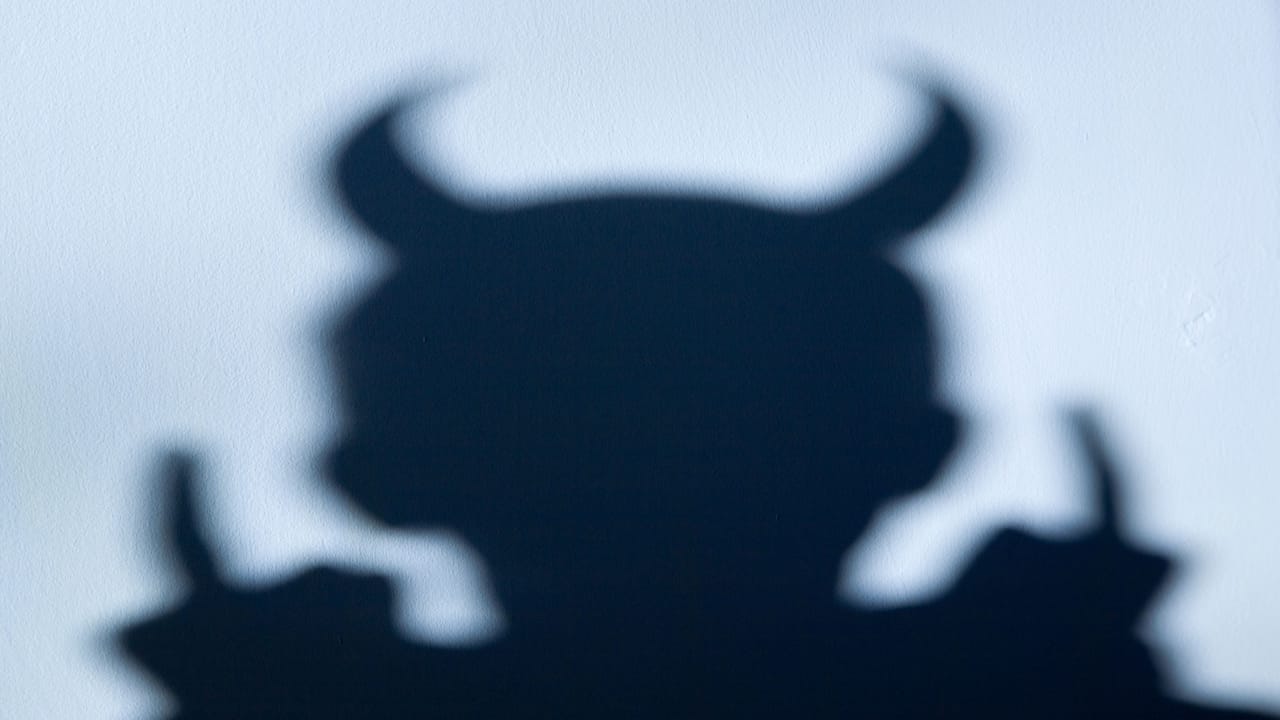 角のある悪魔の影が淡い青色の壁に映っている 角のある悪魔の影が淡い青色の壁に映っている