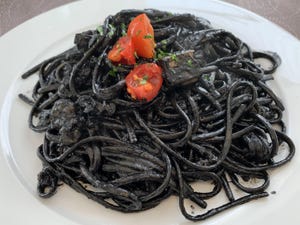 Black noodles with tomatoes on top