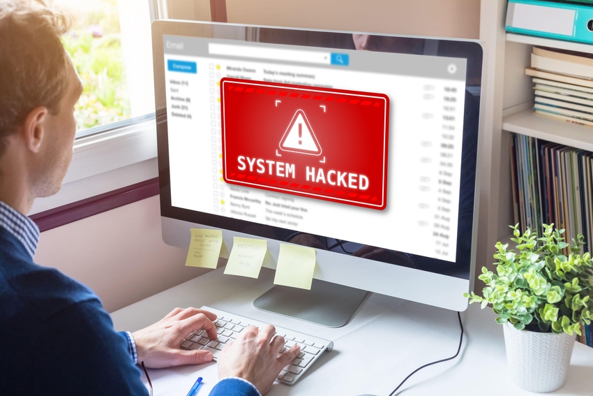 Person sitting at a computer, and the screen reads "System hacked"