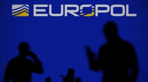 Europol logo on an LED screen with silhouetted people using smartphones in the foreground Europol logo on an LED screen with silhouetted people using smartphones in the foreground