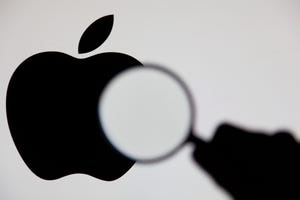 A magnifying glass being held up in front of the apple logo