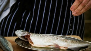 A chef seasoning a fish with salt