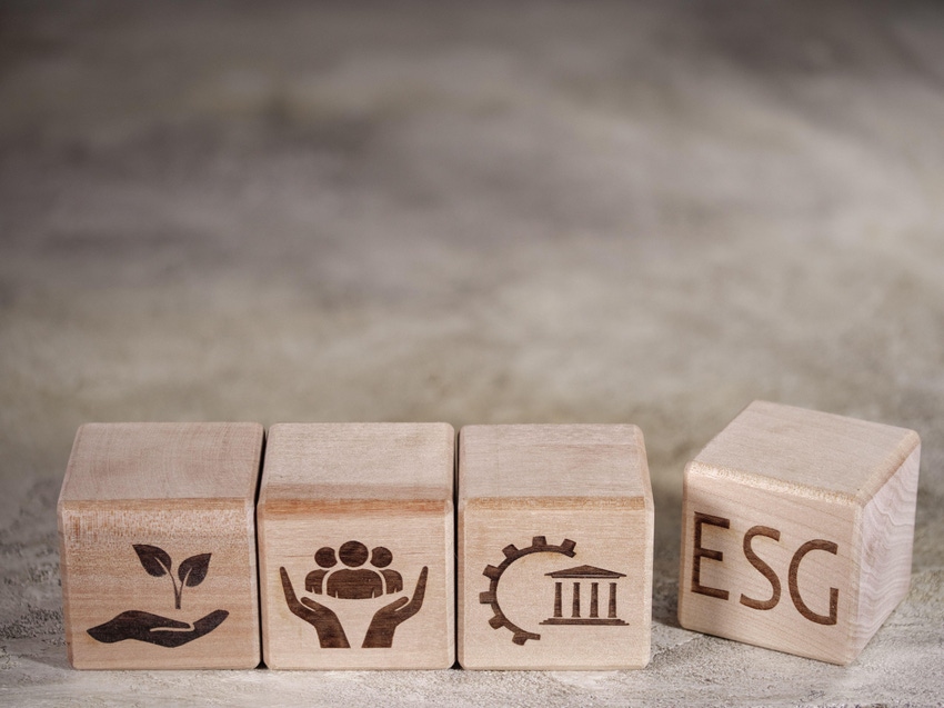 Wooden blocks with icons environmental (hand holding sprout), social (hands cupping people), governance (building), and ESG