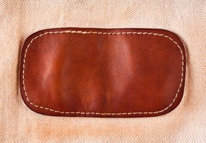 A brown leather patch sewn on fabric