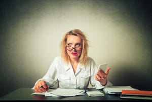 Frazzled business woman with smartphone and papers at desk 