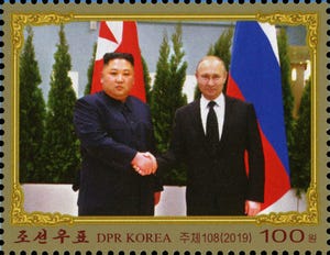 Putin and Kim standing next to each other and shaking hands