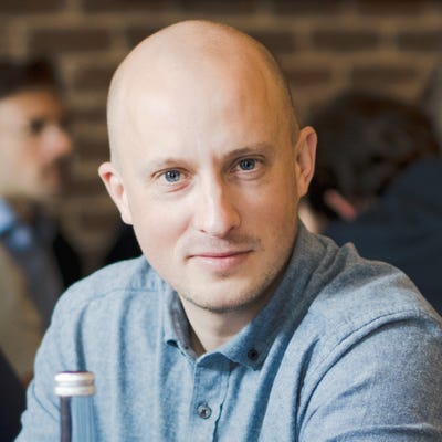 Rory Blundell, CEO of Gravitee, has a shaved head, pale skin, and blue eyes. He's wearing a light blue polo sweater.