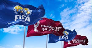 Flags with FIFA and Qatar 2022 World Cup logo waving in the wind.