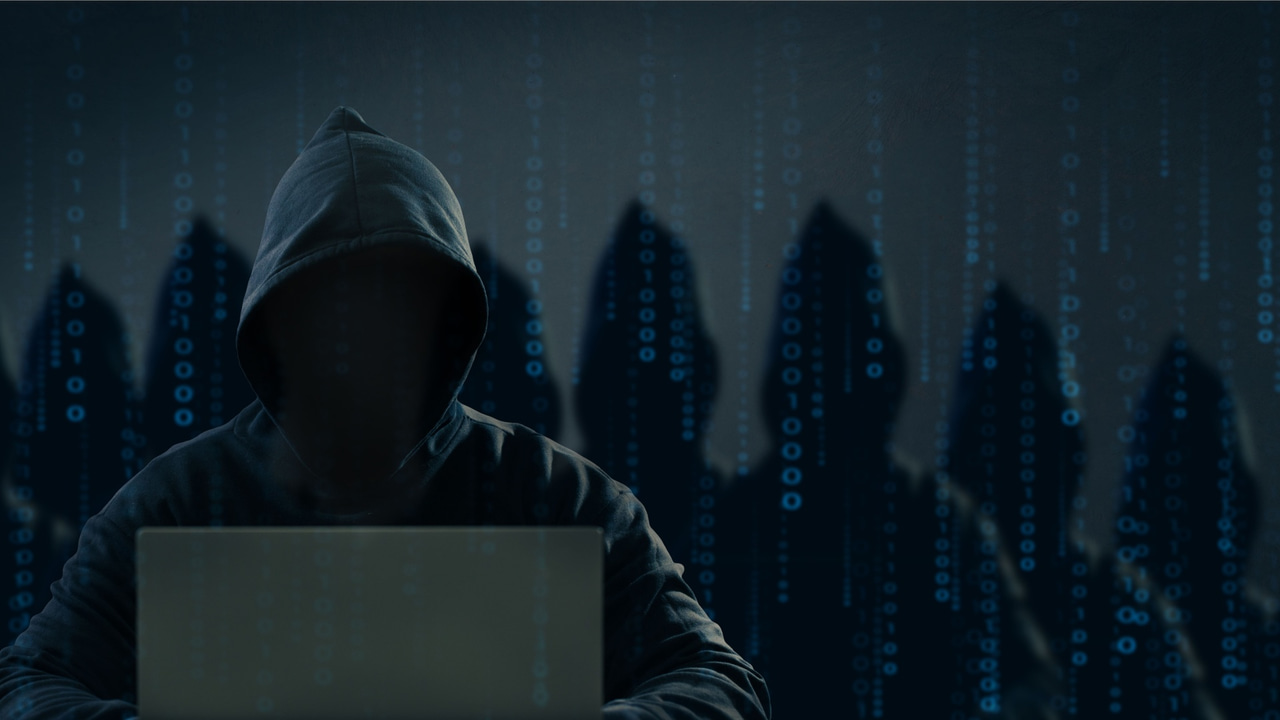 A hooded figure sitting in front of laptop A hooded figure sitting in front of laptop