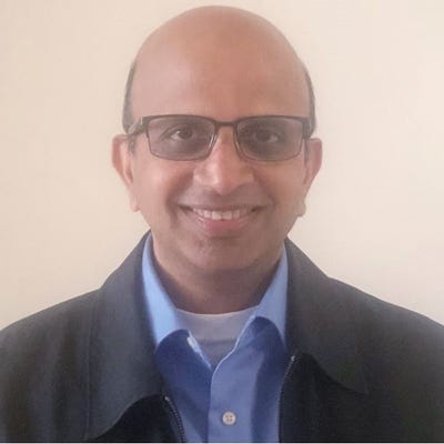 Venkata Josyula, Director in Technology and Product Development, Verizon, has glasses and wears a blue button-down shirt.