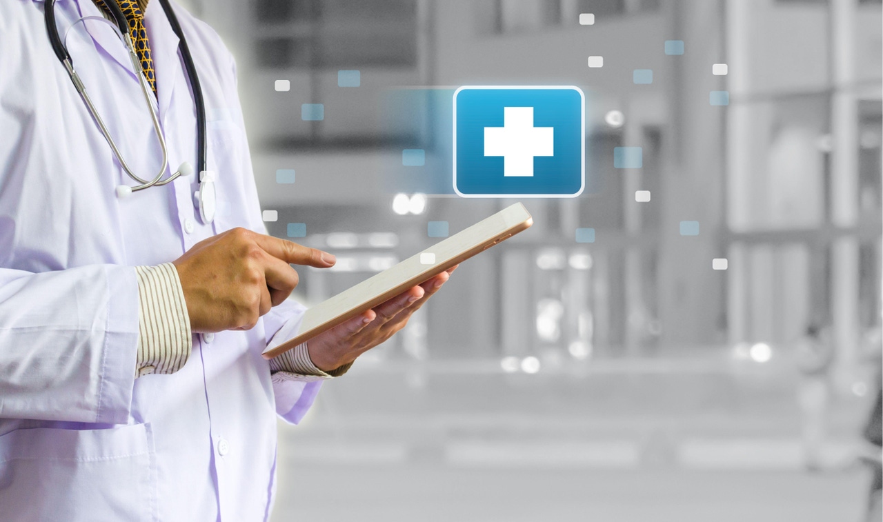 A doctor holding a tablet with a blue and white medical cross symbol hovering over it A doctor holding a tablet with a blue and white medical cross symbol hovering over it