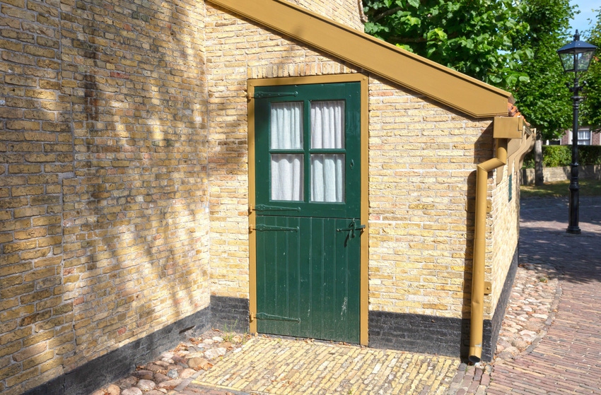 Green door in the side of a tan brick building