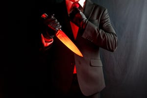 Businessman in dark suit and red tie holding sharp knife. Stylish Assassin and Horror Film Killer.