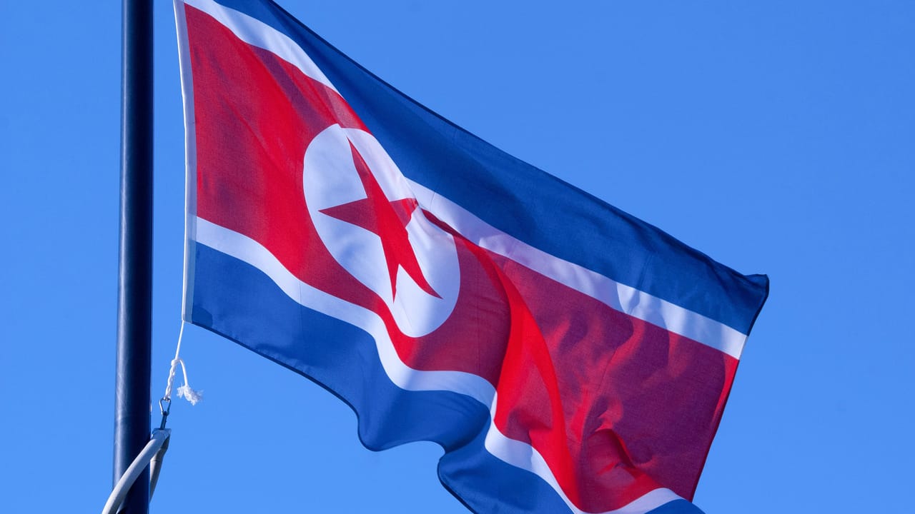 北朝鮮の国旗が旗竿で揺れている、背景は青空 北朝鮮の国旗が旗竿で揺れている、背景は青空