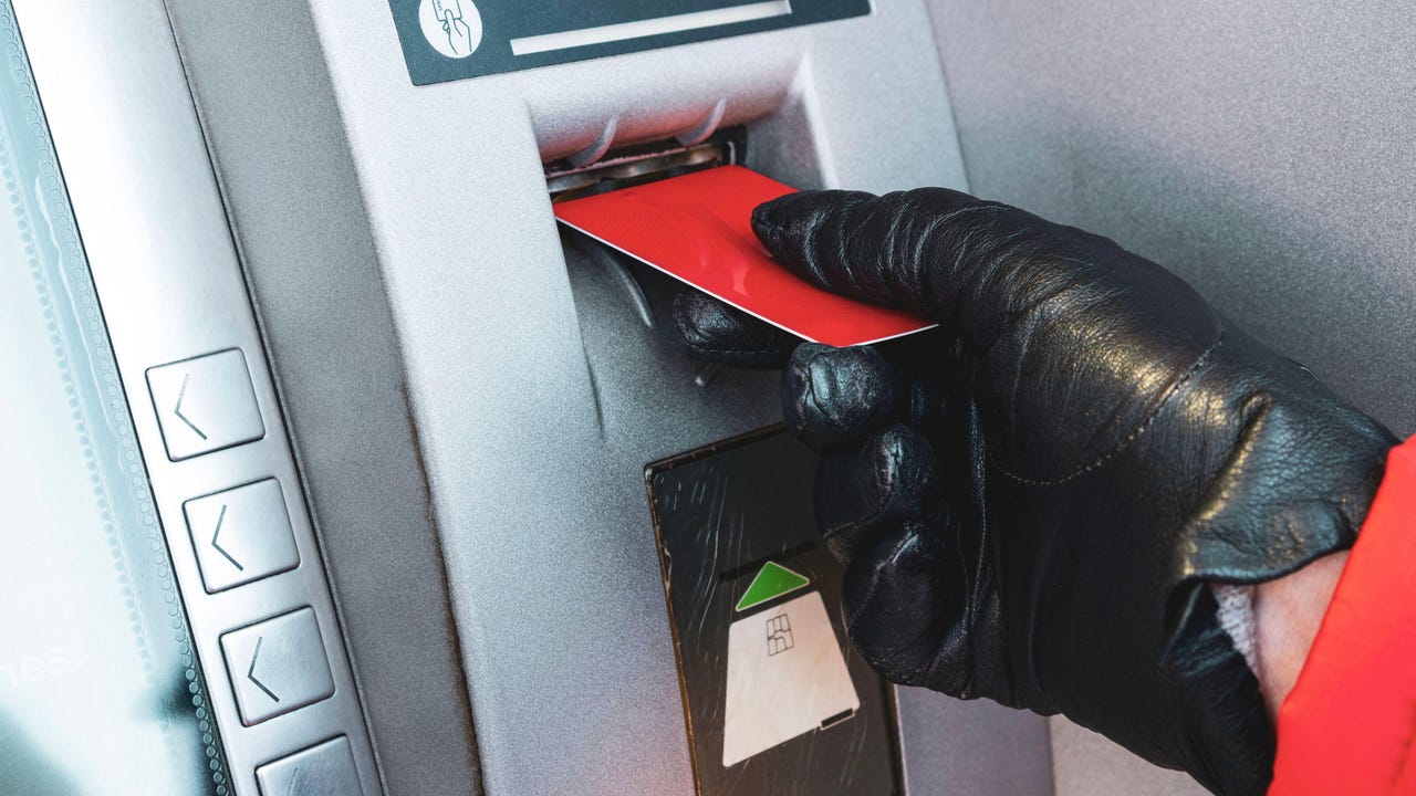 a gloved hand putting a card into an ATM a gloved hand putting a card into an ATM
