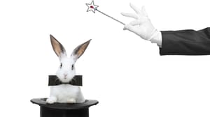 A magician's hand holding a wand, hovering above a bunny wearing a bowtie and sitting in a top hat A magician's hand holding a wand, hovering above a bunny wearing a bowtie and sitting in a top hat