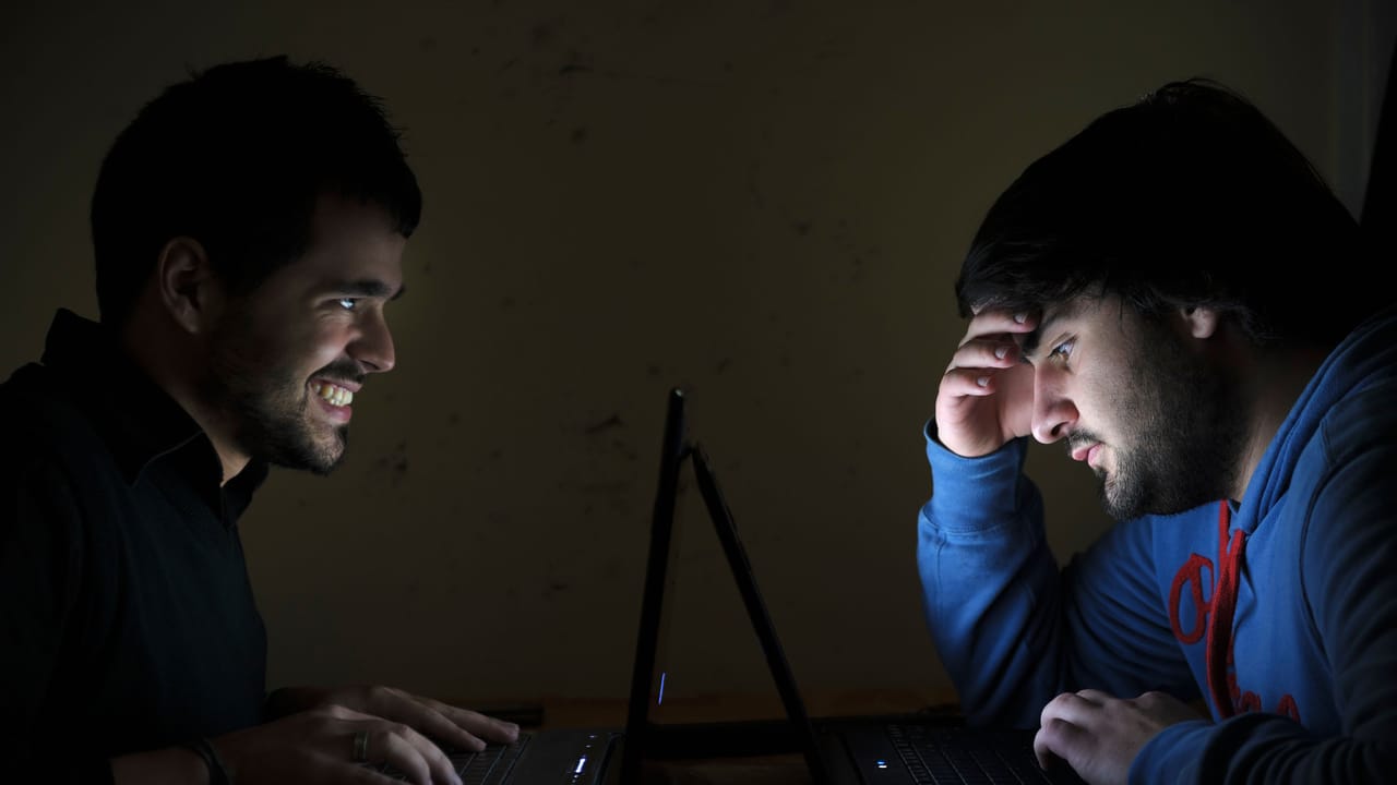 Two young men using laptop computers face to face Two young men using laptop computers face to face