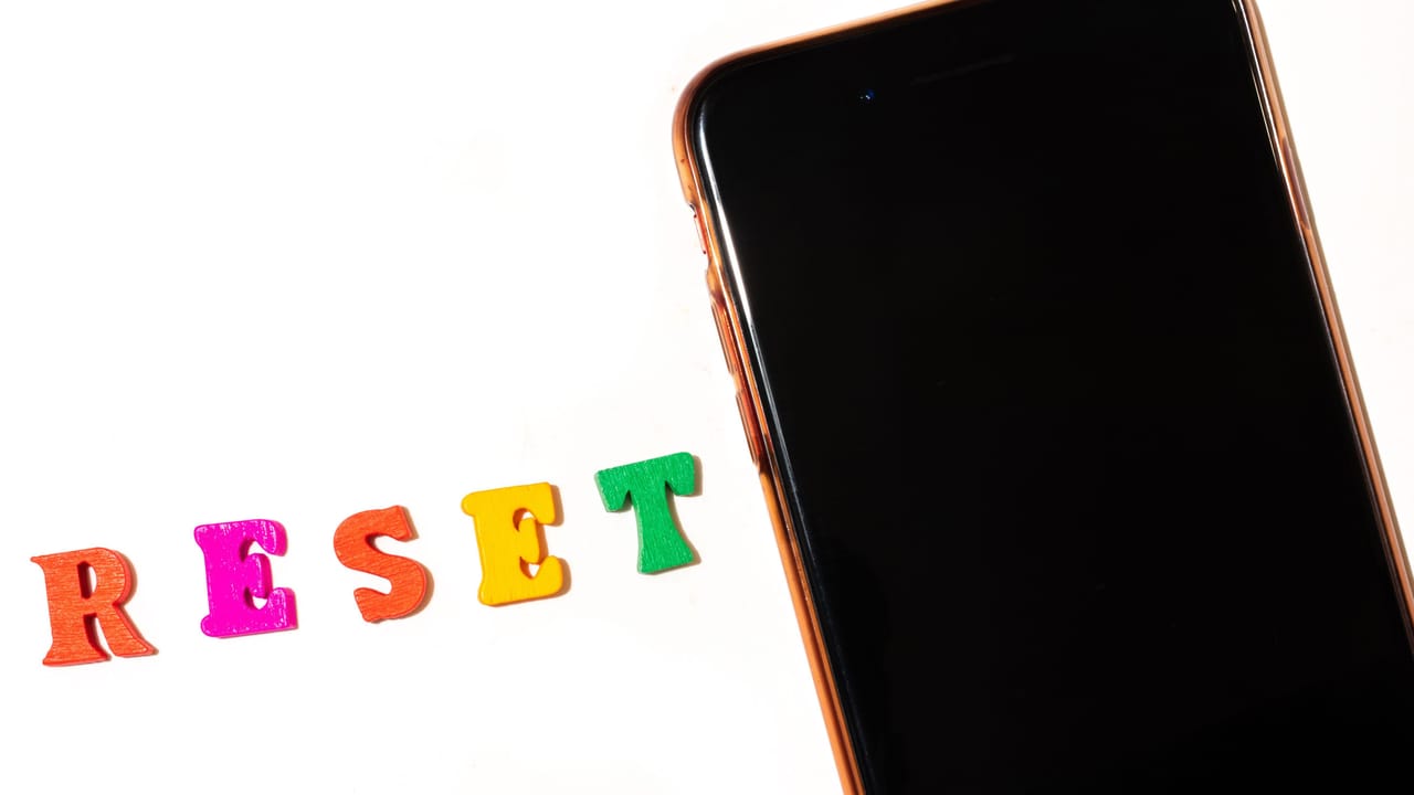 A smartphone with the word "RESET" spelled out next to it A smartphone with the word "RESET" spelled out next to it