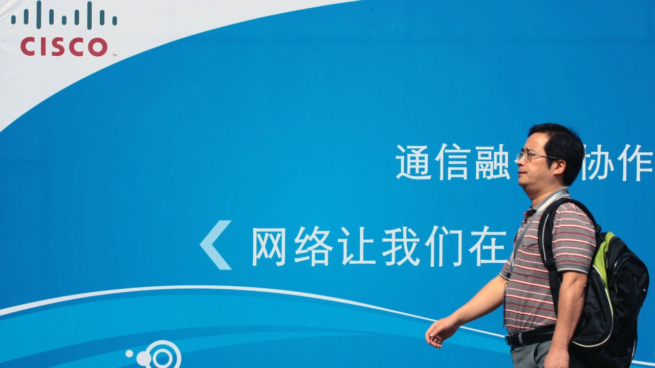 A man walking in front of a Chinese-language Cisco advertisement A man walking in front of a Chinese-language Cisco advertisement