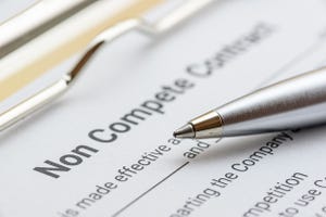 Closeup of a blue pen resting on a noncompete contract on a clipboard