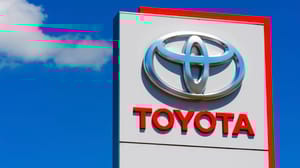 A Toyota sign with blue sky and clouds in the background A Toyota sign with blue sky and clouds in the background