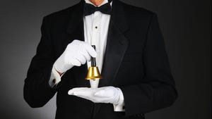 Close-up of a butler wearing a tuxedo and holding a service bell in front of his torso Close-up of a butler wearing a tuxedo and holding a service bell in front of his torso
