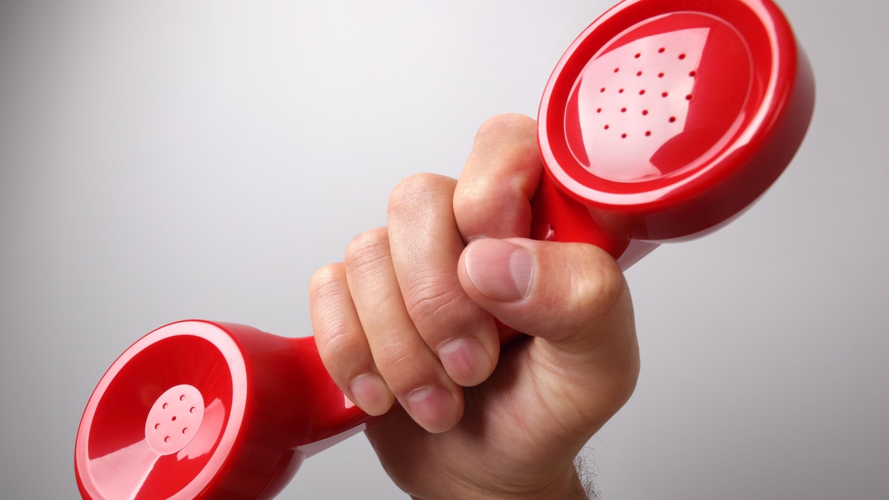 A hand holding a red phone receiver A hand holding a red phone receiver