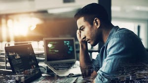 Stressed-out looking man holds his head while looking at his laptop in despair
