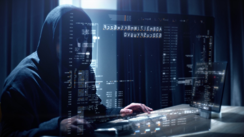 Hooded figure cyberattacker typing on a keyboard; the screen is layered over his image
