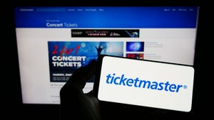 Person holding smartphone with logo Ticketmaster Entertainment Inc. on screen in front of website.