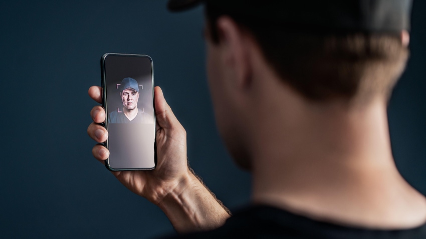 White man in baseball cap taking selfie for facial recognition on smartphone