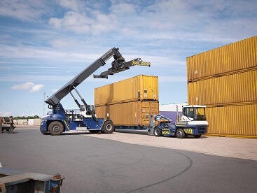 Photo of cranes loading large cargo containers onto the back of trucks