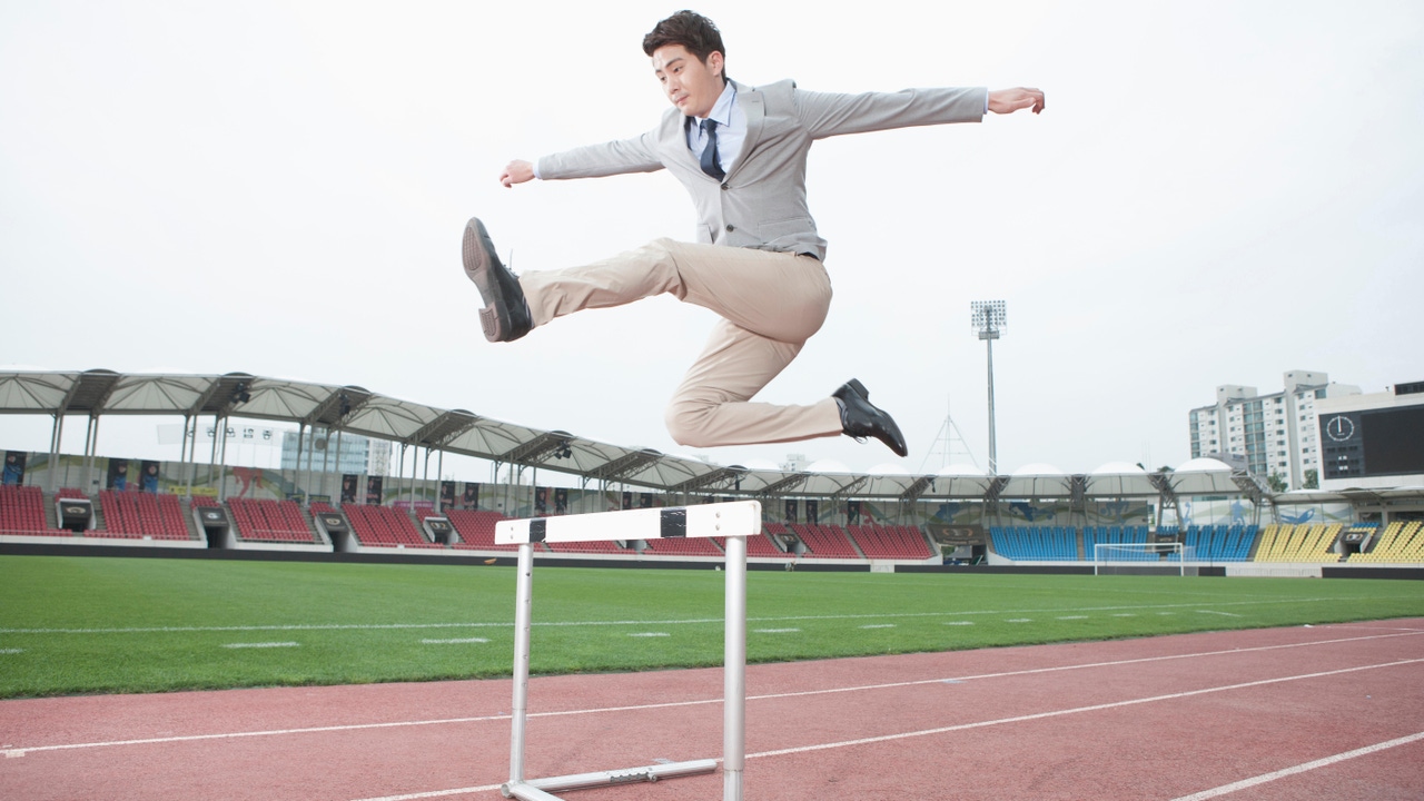 A businessman jumping over a hurdle A businessman jumping over a hurdle