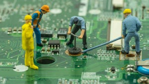 mini workers team try to remove screw from green mainboard