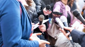 Public figure talking to the media, a crowd of journalists holding microphones at news conference Public figure talking to the media, a crowd of journalists holding microphones at news conference