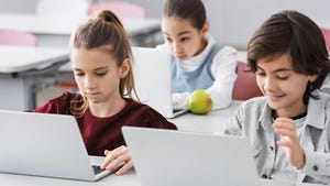 Three children using laptops during a lesson in school Three children using laptops during a lesson in school
