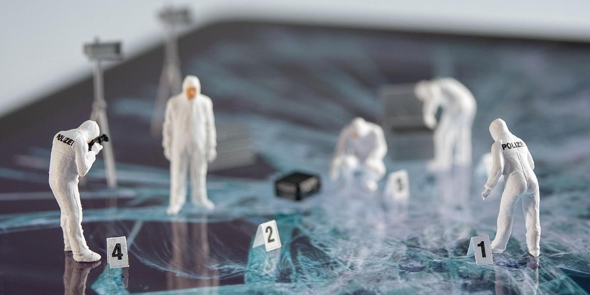 miniature crime scene investigators standing on top of a computer collecting evidence.